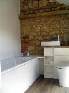 托斯特Toad Hall at Tove Valley Cottages的浴室配有白色浴缸和石墙