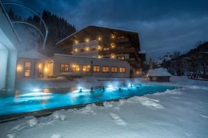 费尔兹姆斯费尔兹姆斯阿尔蓬霍夫兰德酒店的一座在夜间积雪中设有游泳池的建筑