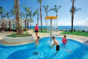 帕福斯亚历山大海滩酒店的一群人在度假村的游泳池玩耍