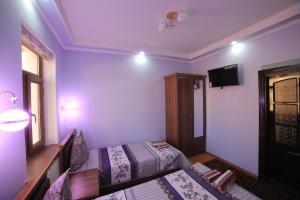 布哈拉Alliance hotel bukhara的客房设有两张床和一台墙上的电视。