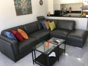 贝纳尔马德纳Avda de las Palmeras Apartment的一张带彩色枕头和桌子的黑色皮沙发