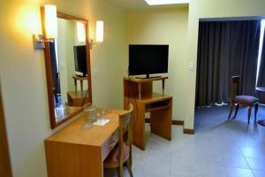 加拉加斯Hotel Coliseo的酒店客房设有电视和带镜子的书桌