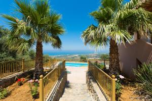 马鲁拉斯Maroulas Villas Ioanna & Stavros, stunning views, By ThinkVilla的拥有两棵棕榈树和游泳池的度假村