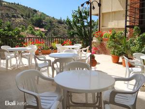 卡科佩特里亚埃卡利酒店的庭院里摆放着一组桌子和白色椅子