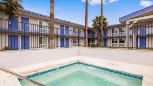 萨克拉门托SureStay Plus Hotel by Best Western Sacramento Cal Expo的棕榈树建筑前的游泳池