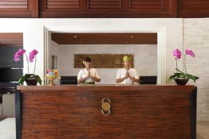沙努尔格莱亚桑川海滩度假酒店的两个人手臂交叉站在柜台