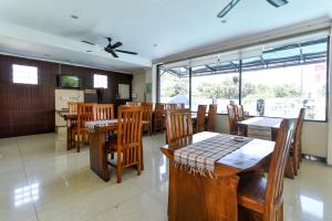 登巴萨RedDoorz Plus near Mall Bali Galeria 2的餐厅设有木桌、椅子和窗户。