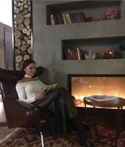 比什凯克比什凯克布古酒店的坐在椅子上读一本壁炉旁的书的女人