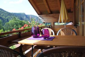 奥伯斯特多夫Landhaus Schmid的阳台上配有一张带椅子的木桌和紫色花瓶