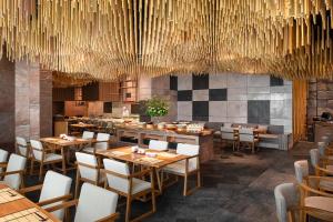 曼谷曼谷日航酒店的餐厅设有木桌、椅子和吊灯。