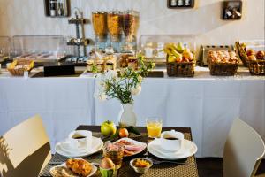 莫吉奥Forme-hotel & Spa Montpellier Sud-Est - Parc Expositions - Arena的桌子,上面有杯子和盘子,食物和饮料