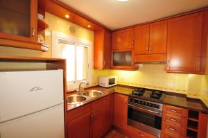 圣苏珊娜HomeHolidaysRentals Aqua的厨房配有木制橱柜、水槽和冰箱。