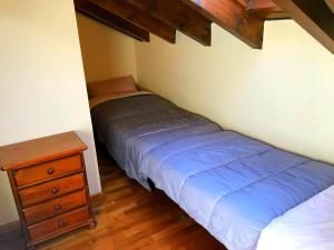 贝尔维尔德赛当亚Bonito ático en Bellver de Cerdanya的一间卧室配有一张床和一个木制梳妆台