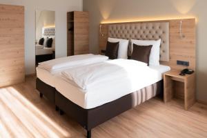安斯巴赫Rossano Boutique Hotel & Ristorante的一间卧室配有一张大床和大床头板