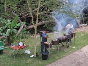 谢普斯敦港Dieu Donnee River Lodge的草上烤架上的人做饭