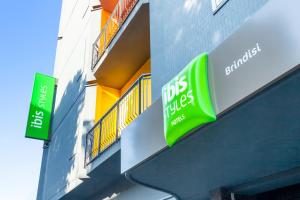 布林迪西Ibis Styles Brindisi的建筑一侧有两个绿色标志的商店