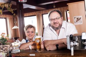 BrauneggBraunegger-Hof Gasthof Mayer的坐在酒吧里喝啤酒的男人和女人