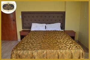 利马Dubai Palace的一张位于酒店客房内的床铺,配有金色床罩