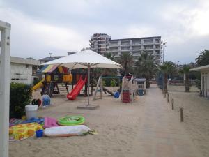 朱利亚诺瓦FRONTE MARE-CENTRALE-Riviera Palace-Giulianova-Apartment-nei mesi di Giugno Luglio e Agosto Prenotazioni solo da Sabato a Sabato的海滩上设有带遮阳伞和滑梯的游乐场