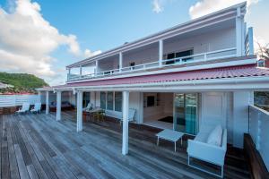 古斯塔维亚Penthouse de Luxe Gustavia的房屋设有大甲板和椅子