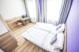 林茨特姆法克酒店的一间卧室配有带白色床单和枕头的床。