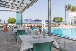 卡门港拉斯科斯塔斯酒店的一间带桌椅的餐厅和一个游泳池