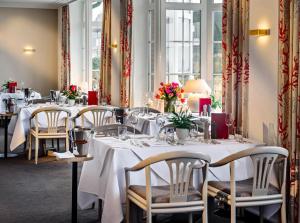 坎彭鸿恩霍尔特酒店的餐厅设有白色的桌椅和鲜花