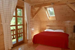 拉科维察吉洛维克纳拉农场酒店的小木屋内一间卧室,配有红色的床