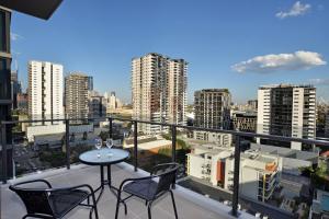 布里斯班Brisbane One Apartments by CLLIX的一个带桌子和两把椅子的阳台和一个城市