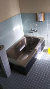伊势市太江寺宿坊旅舍的浴室里设有不锈钢浴缸,铺有蓝色瓷砖