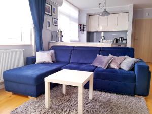 加茨比亚格拉ApartMorze apartamenty Fregata的客厅里配有一张带白色桌子的蓝色沙发