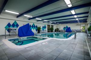 利物浦Holiday Inn & Suites Syracuse Airport - Liverpool, an IHG Hotel的大楼内带蓝色椅子的大型游泳池