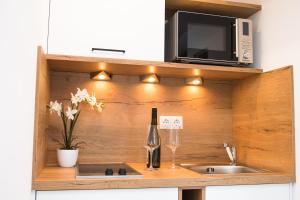 库夫施泰因Your Home - City Apartment in Kufstein的厨房配有水槽、微波炉和一瓶葡萄酒
