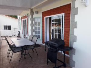 洛尼湾村Bonne View Villa的一个带烧烤架和桌椅的庭院