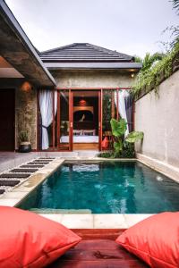 坎古La Isla Villas Bali的房屋前的游泳池,配有红色枕头