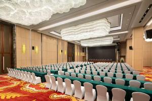 新郑郑州景瑞华美达酒店的空的讲堂,有白色的椅子和屏幕