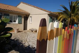 GaronsLa Maison de Peggy的房屋旁的围栏,上面有冲浪板