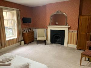 巴恩斯利Wortley Hall Sheffield的一间卧室设有壁炉、椅子和镜子