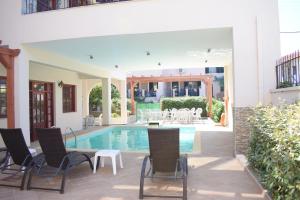 米里纳艾菲斯酒店的庭院设有游泳池、椅子和桌子。