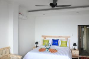 艾湄湾阿卢尔海滩民宿的卧室配有白色的床和吊扇