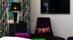 卑尔根13号酒店的卧室配有椅子和墙上的电视