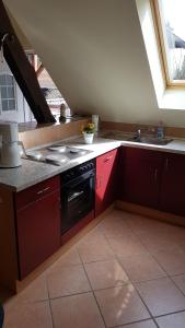 NiedergörsdorfUrlaubsscheune的厨房配有红色橱柜、炉灶和水槽。