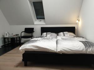 伊本比伦Pension Pommernweg Ibbenbüren的一间卧室配有一张带白色床单和椅子的床