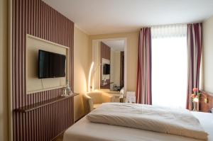 特罗斯多夫普利姆勒酒店的酒店客房,设有床铺和墙上的电视