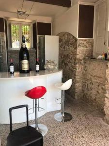 维博瓦伦蒂亚码头B&B Villa Delle Rondini的厨房设有酒吧,配有红色凳子和葡萄酒瓶