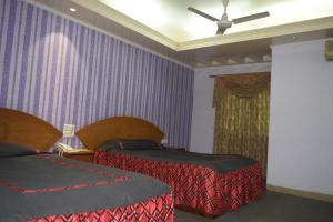 吉大港Asian SR Hotel的酒店客房设有两张床和紫色的墙壁。