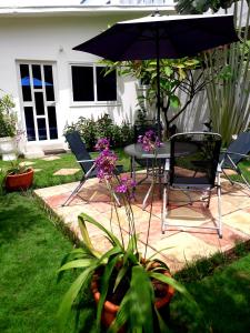 科托努L'Epicurien的庭院配有桌椅和遮阳伞。