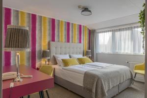 登霍伦欧普德克酒店的一间卧室配有一张床、一张书桌和色彩缤纷的墙壁