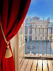 都灵Corte Realdi Luxury Rooms Torino的窗户配有红色窗帘,享有建筑的景致