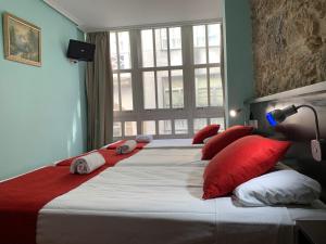 拉科鲁尼亚Hostal Hotil Coruña Centro的一间卧室配有两张带红色枕头的大床